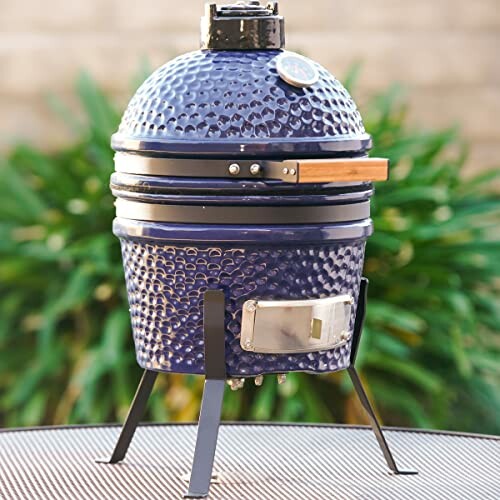 Blue ceramic kamado grill on a stand outdoors.