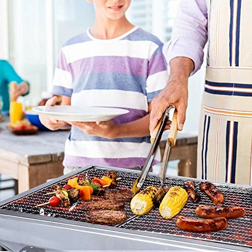 Person grilling corn and sausages on a barbecue with a child holding a plate nearby.